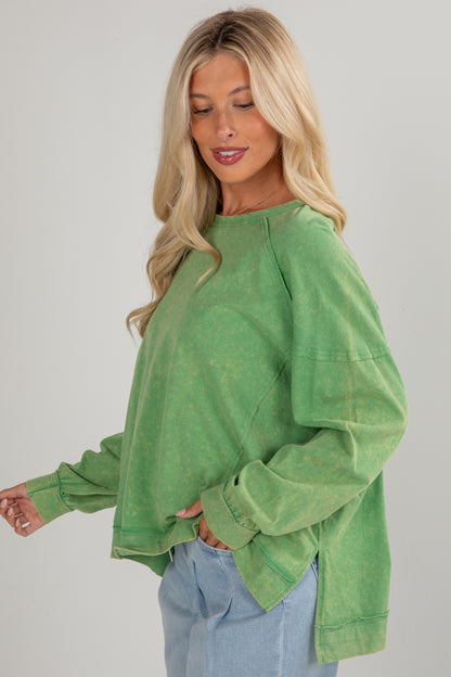 Woman wearing a green oversized sweater against a plain background