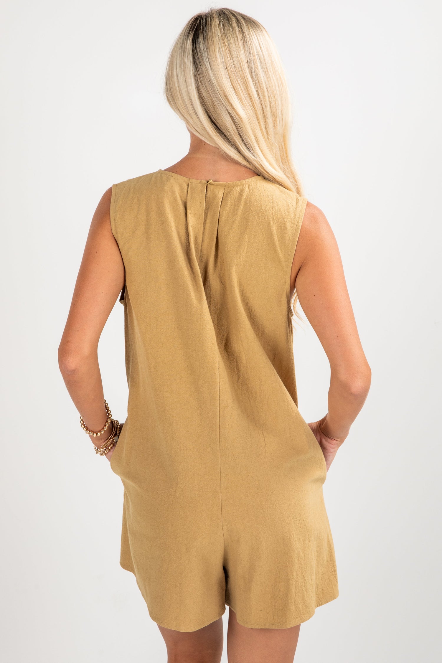 Woman wearing a mustard yellow sleeveless dress on a white background