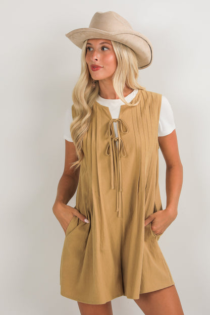 Woman wearing a beige sleeveless dress and hat on a white background