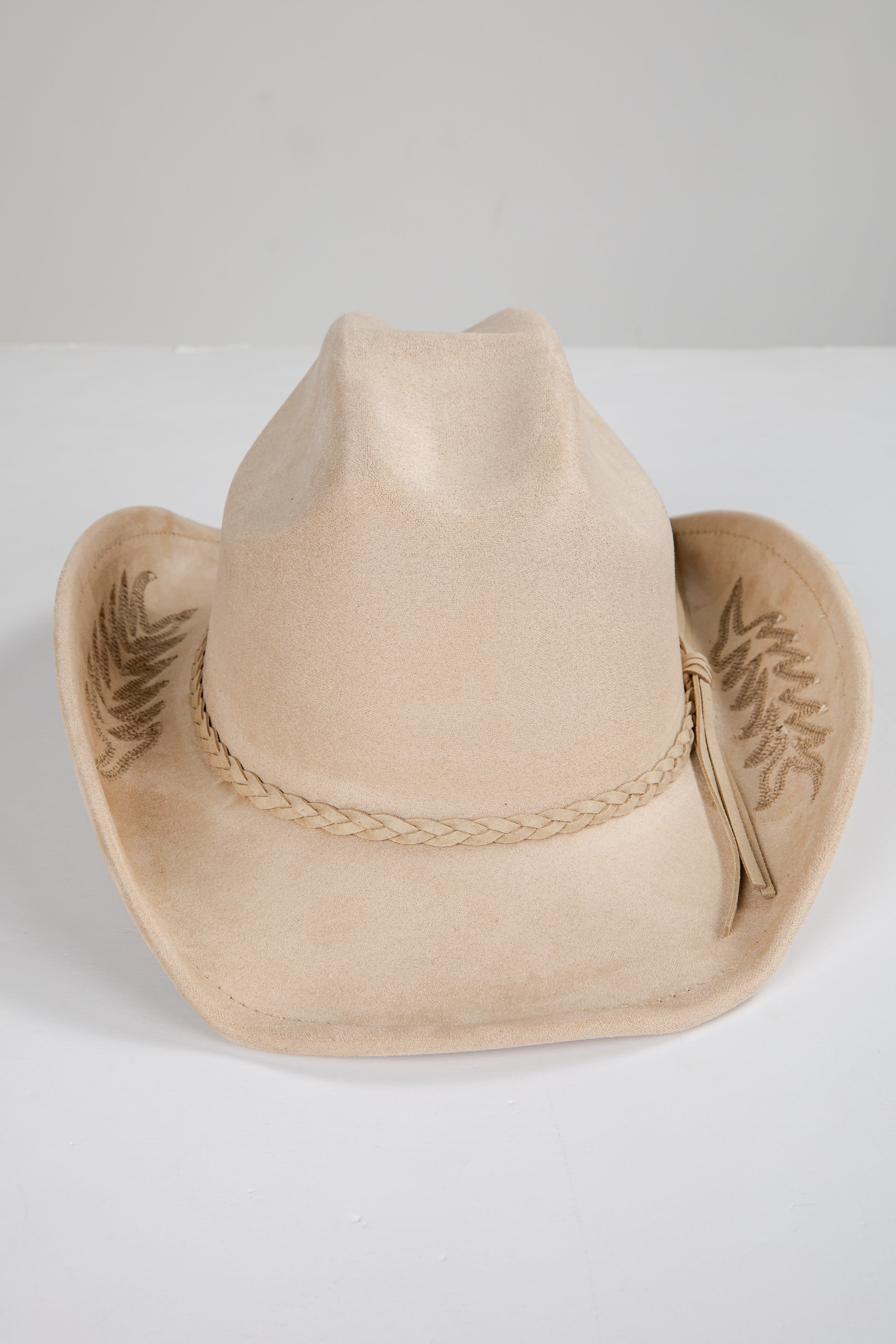Beige cowboy hat with braided band on a white background