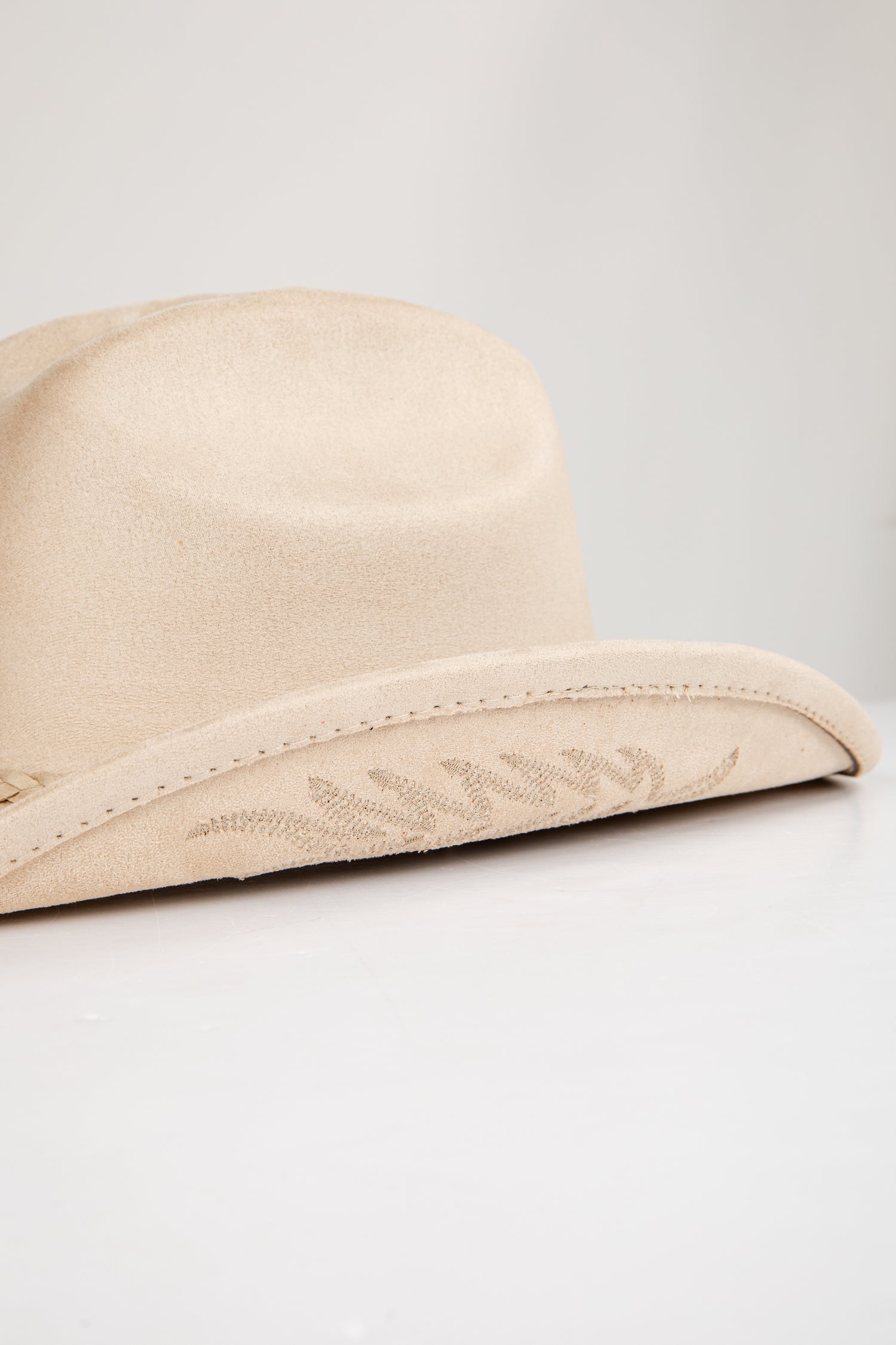 Beige hat with floral embroidery on a light gray background