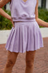 Person wearing a light purple sleeveless top and skirt set with a blurred background