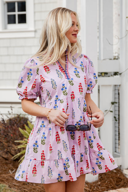 Woman wearing a floral dress standing outdoors near a white building.