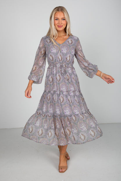 Woman wearing a patterned dress against a plain background