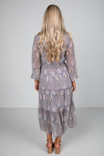 Woman wearing a patterned dress with long hair on a plain background