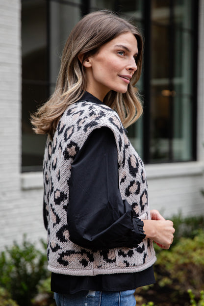 Woman wearing a leopard print vest over a black top outdoors.