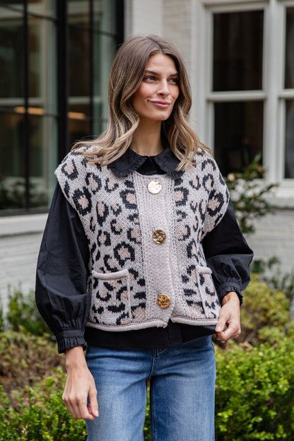 Woman wearing a leopard print vest with black sleeves outdoors.
