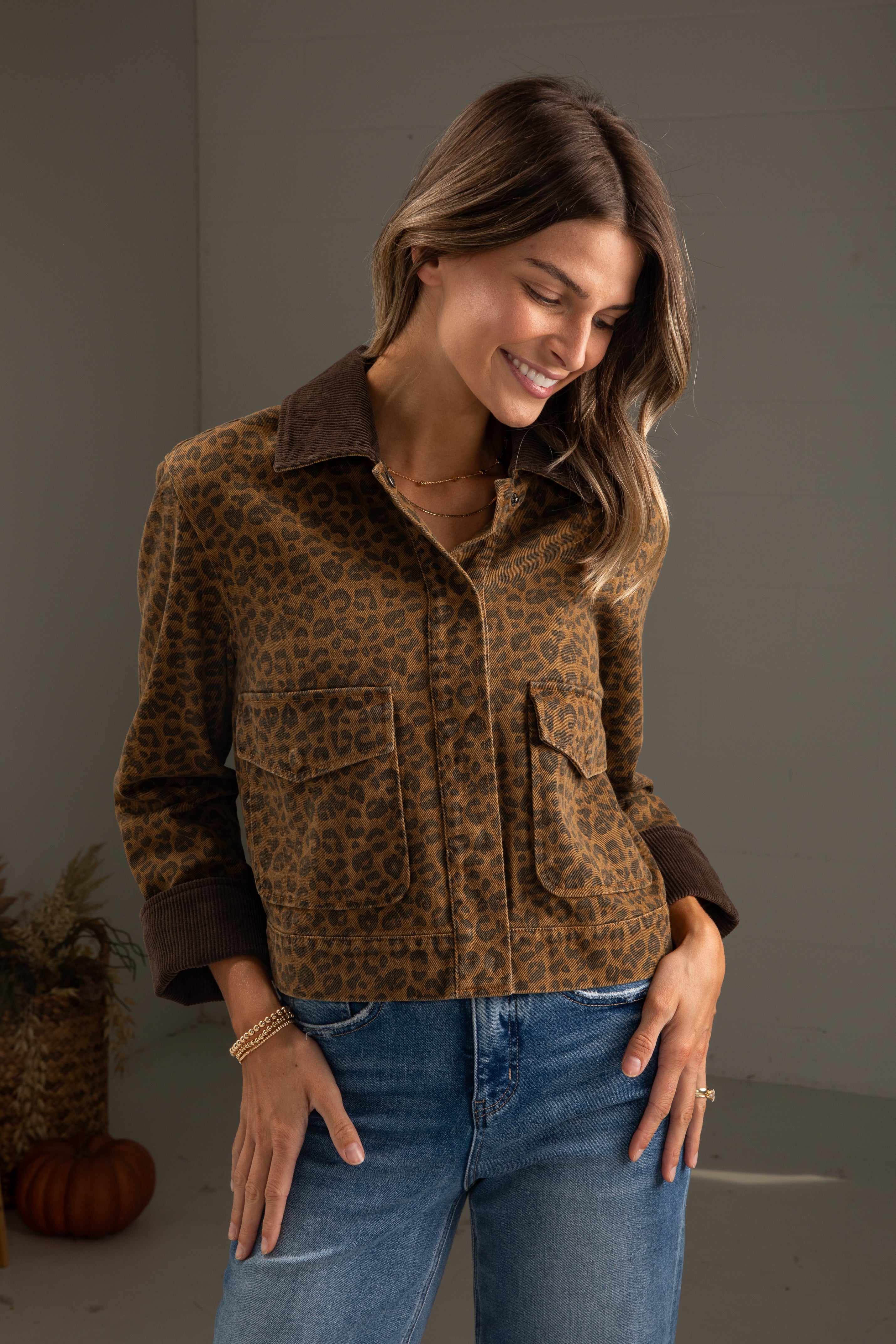Woman wearing a leopard print shirt and blue jeans against a neutral background