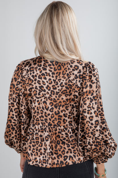 Person wearing a leopard print blouse against a plain background