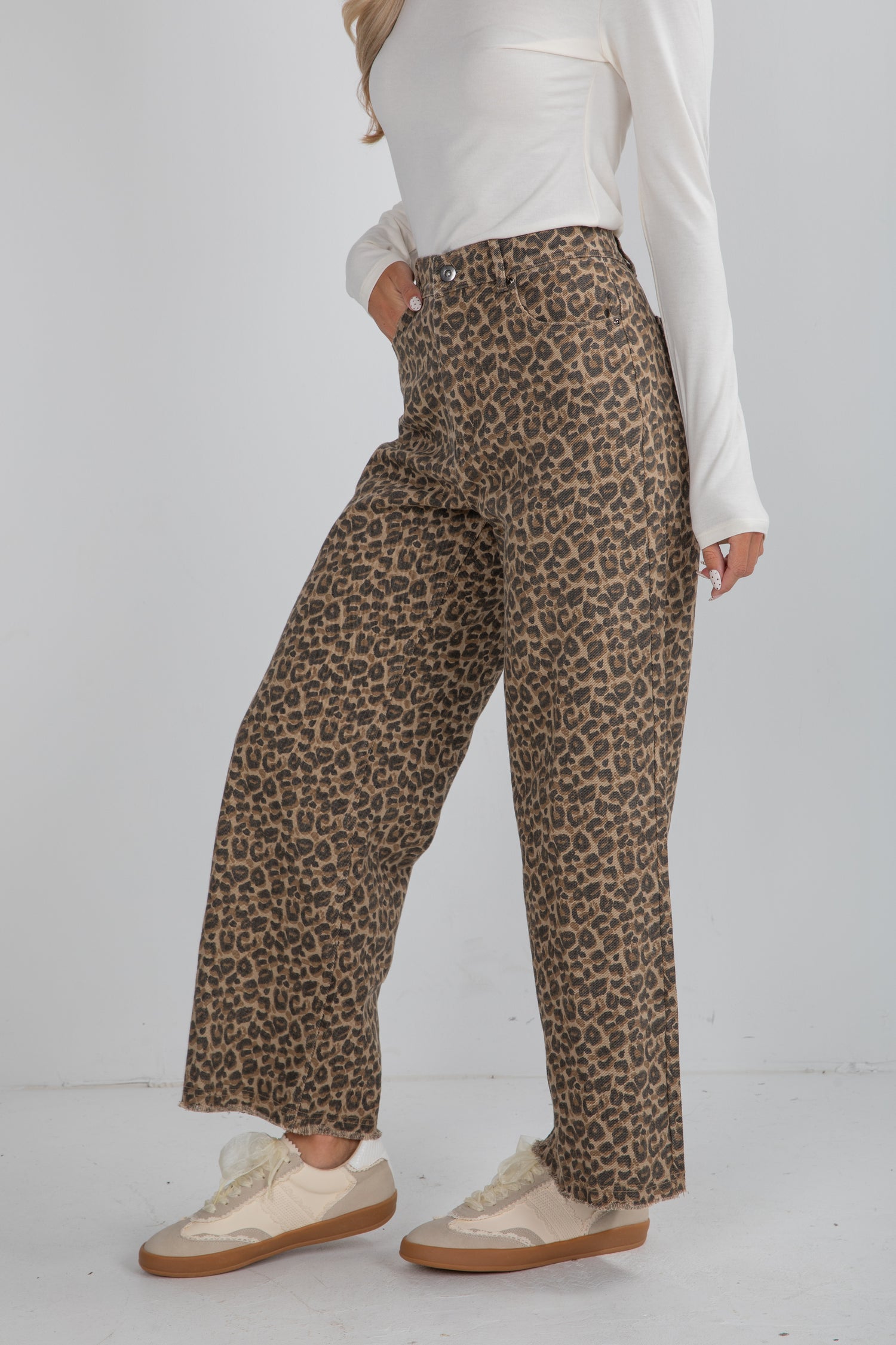 Person wearing leopard print pants and a white top on a white background