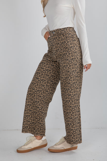 Person wearing leopard print pants and a white top on a white background