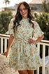 Woman wearing a spring floral mini dress with sunglasses and gold bracelets