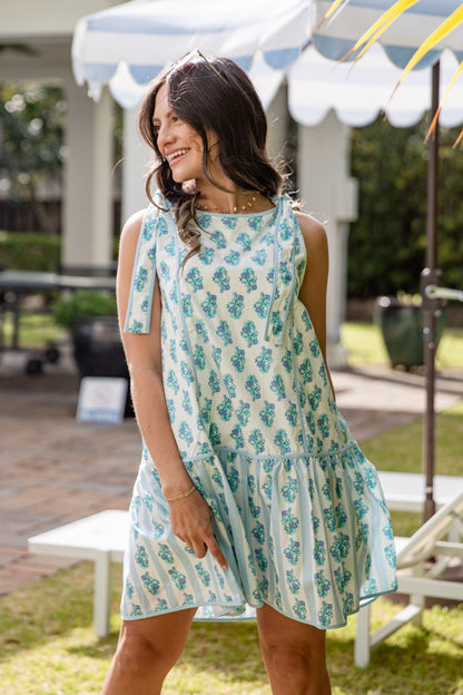 Woman wearing a floral dress standing outdoors under a canopy.