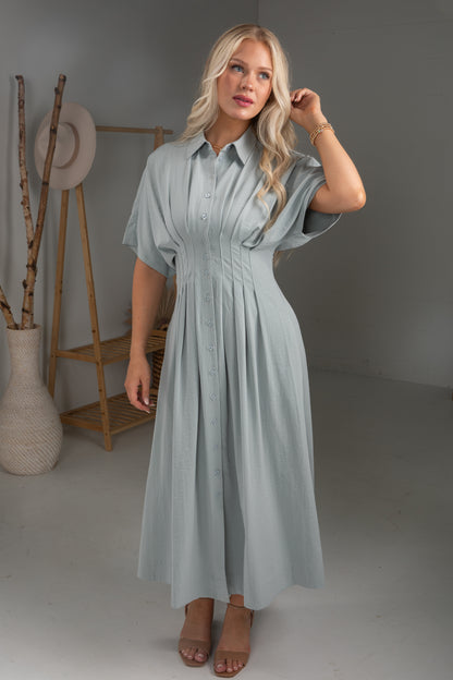 Woman wearing a light blue dress in a minimalistic room.
