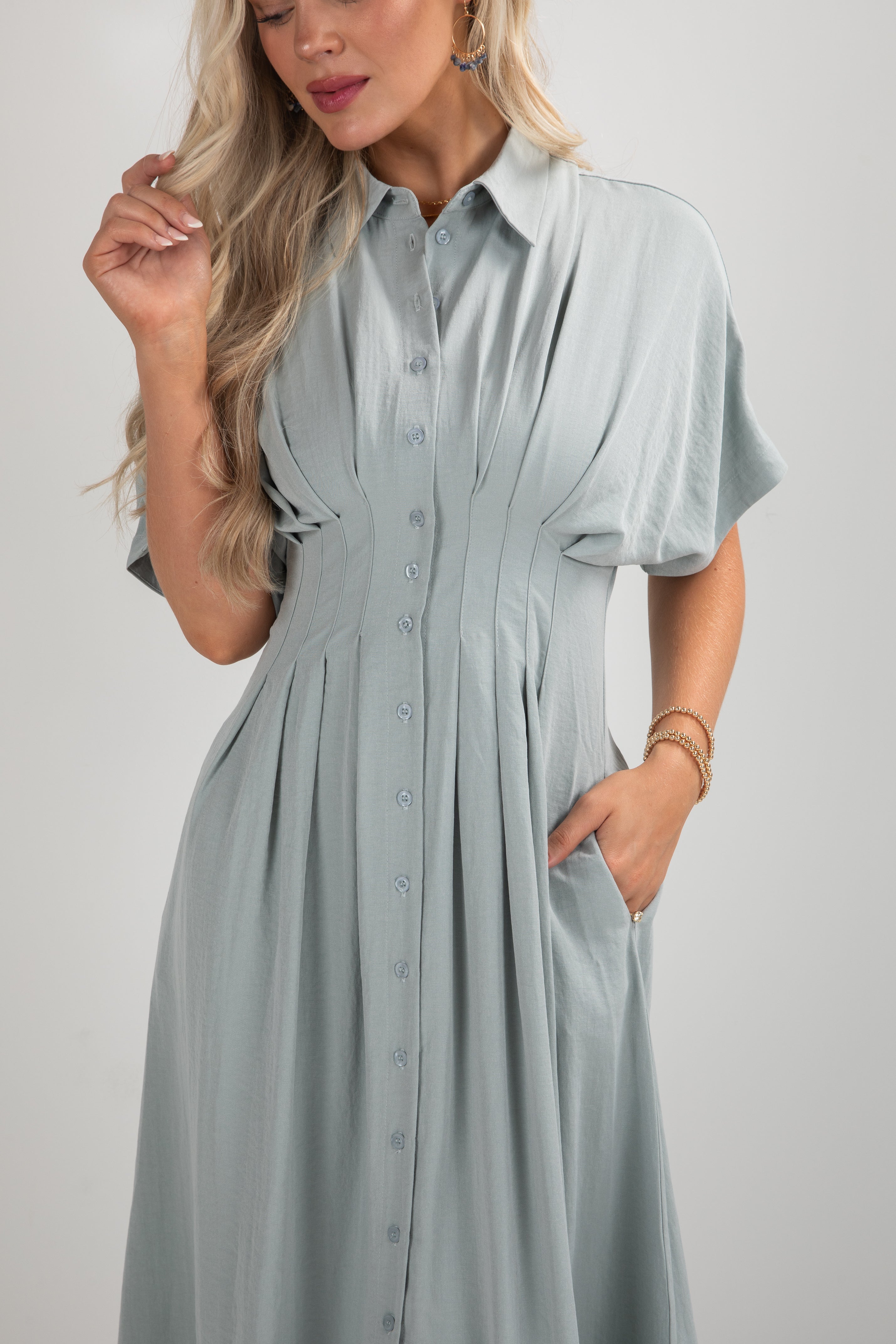 Woman wearing a light blue dress with short sleeves on a plain background