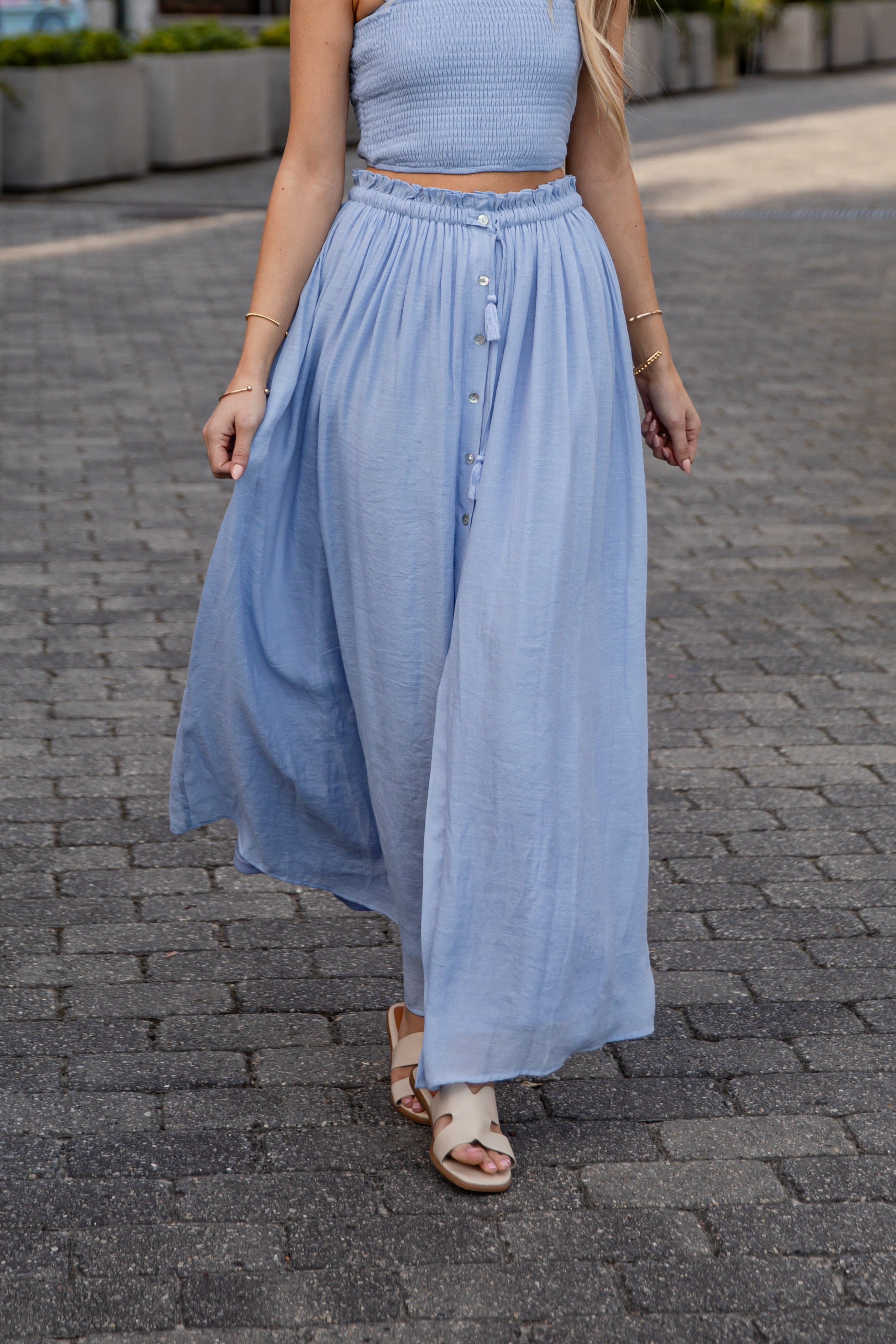 Woman wearing a light blue dress on a paved street.