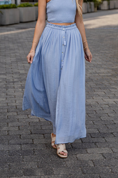Woman wearing a light blue dress on a paved street.