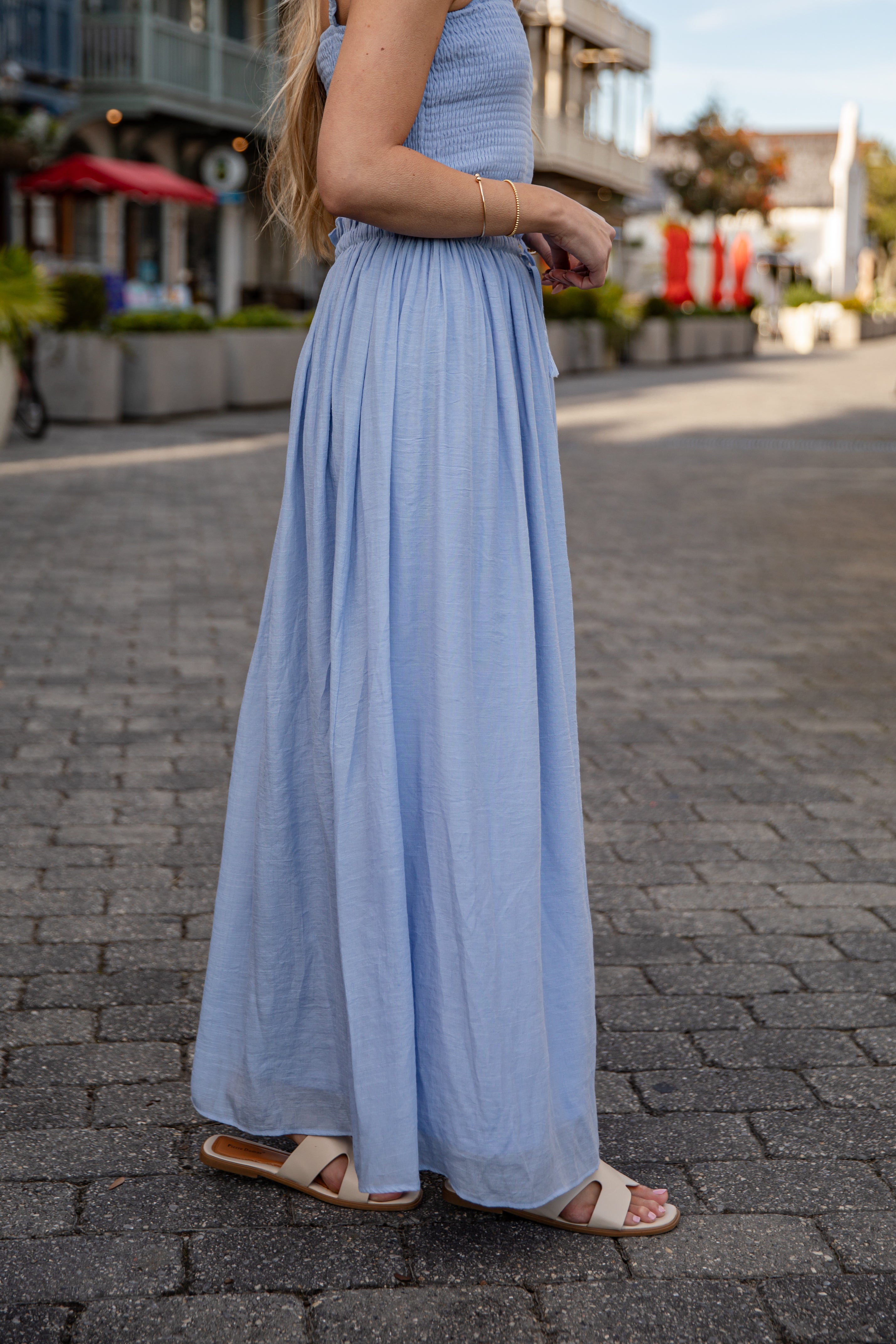 Woman wearing a long light blue dress on a street with blurred background