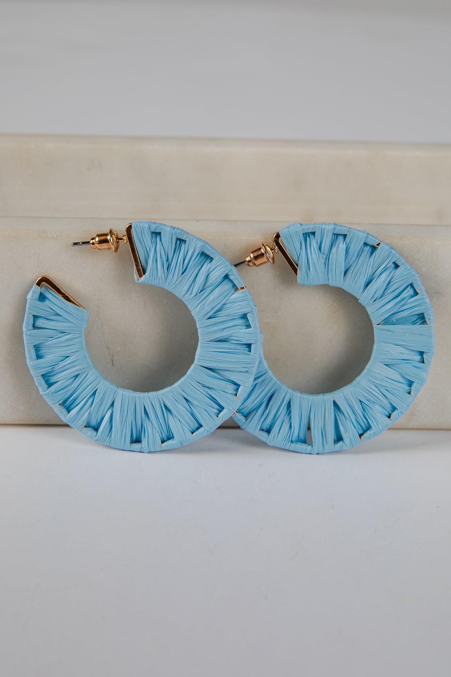 Light blue hoop earrings with ruffled edges on a light background