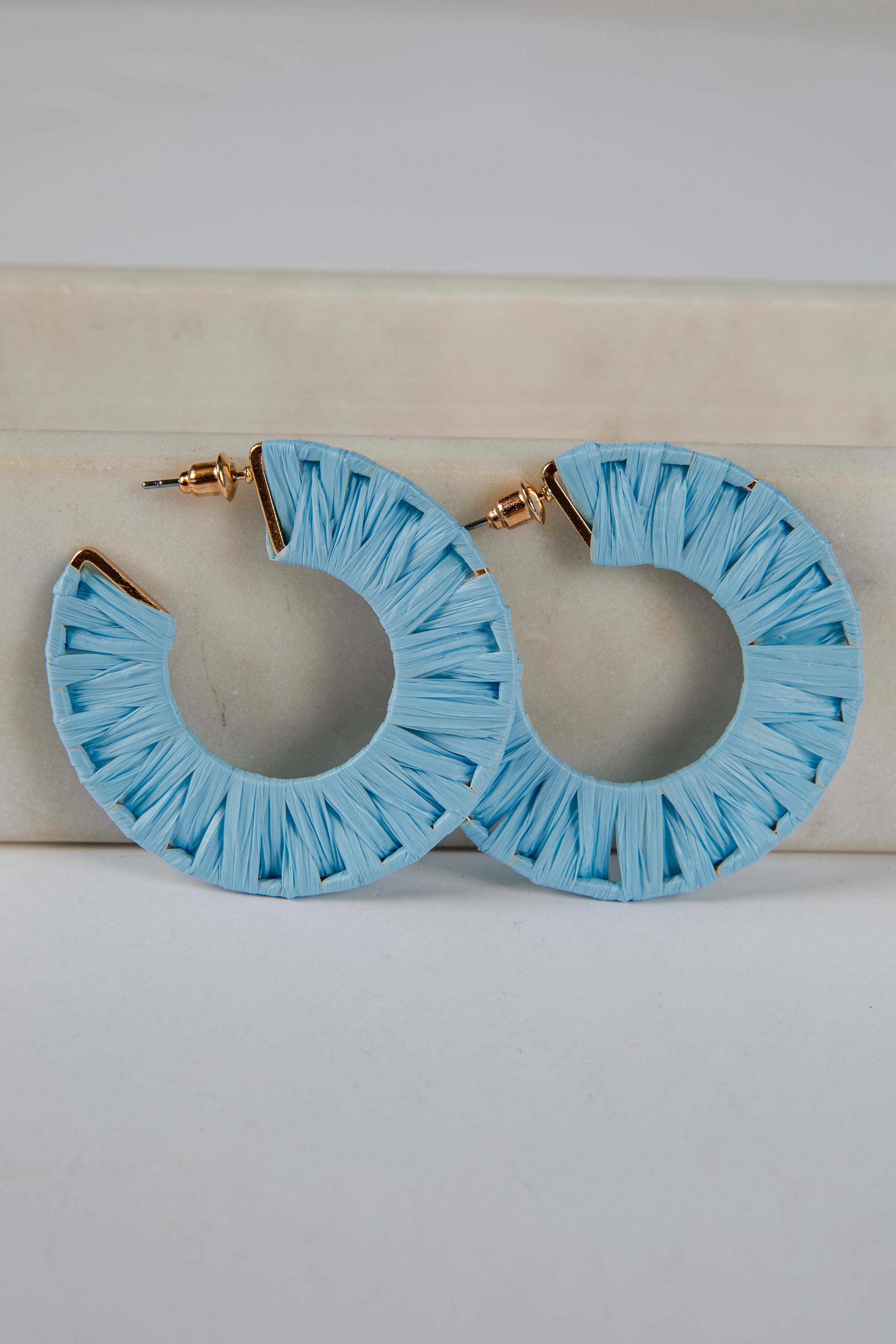 Light blue hoop earrings with ruffled edges on a light background