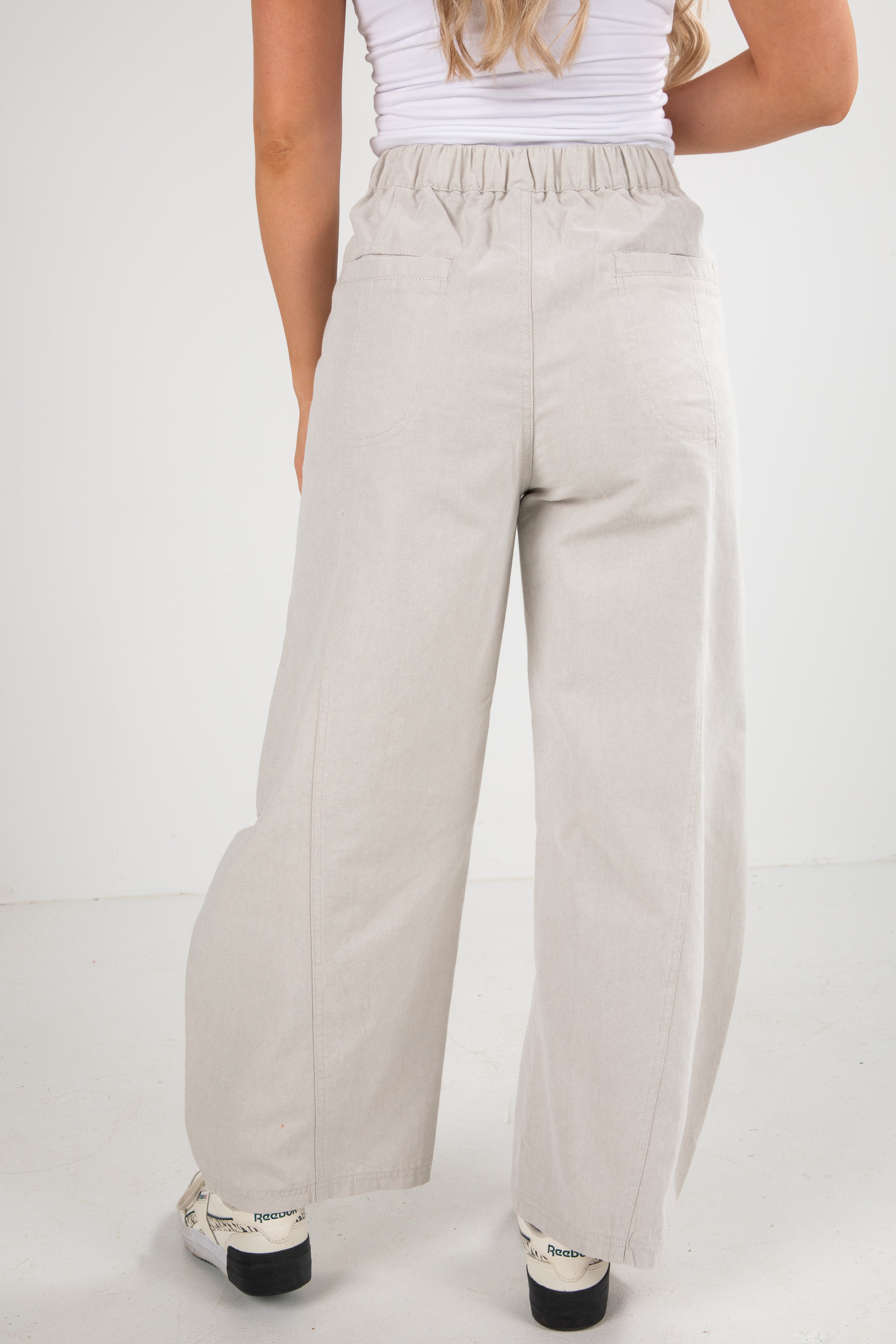 Person wearing light gray wide-leg pants on a white background