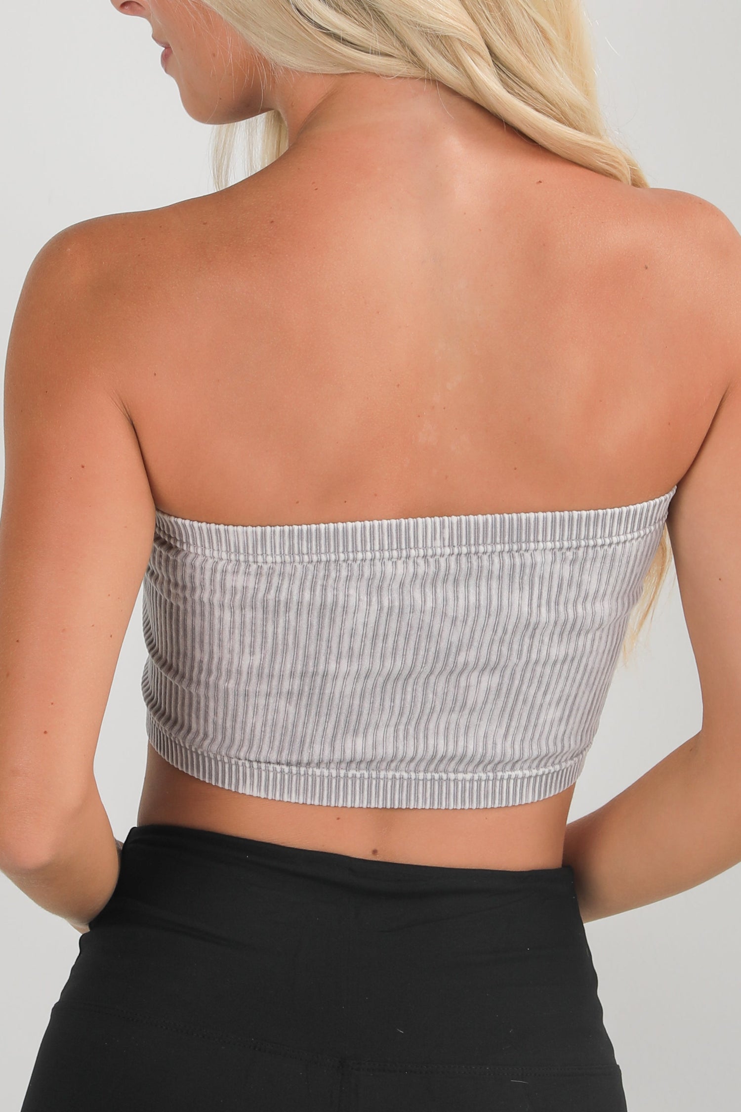 Woman wearing a gray strapless top with a white background