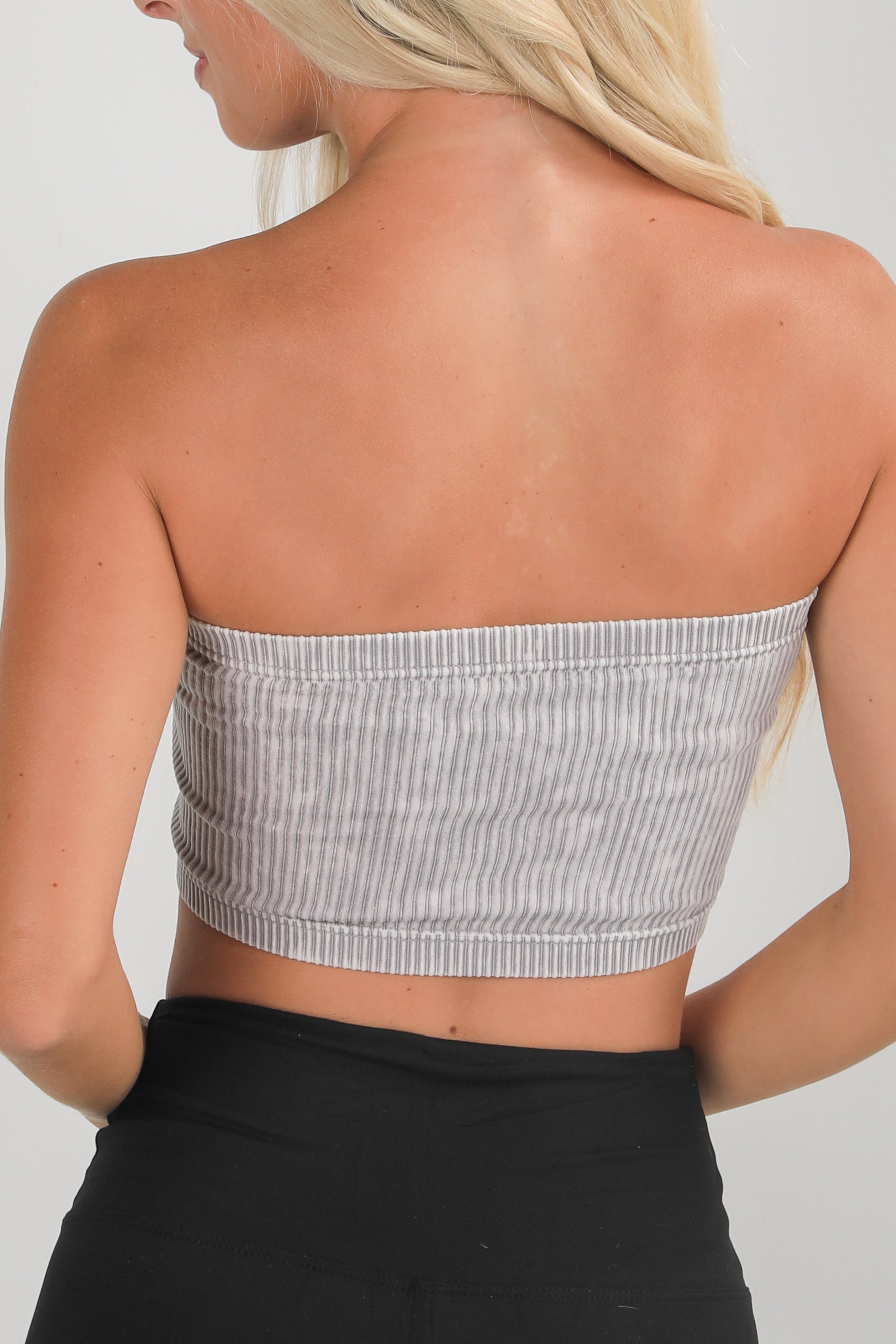 Woman wearing a gray strapless top with a white background