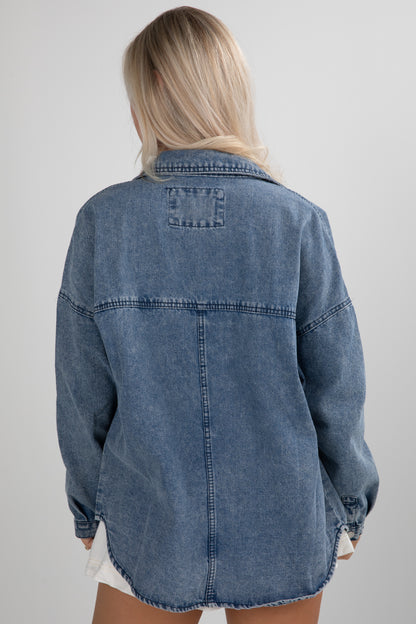 Blue denim jacket worn by a person on a plain background