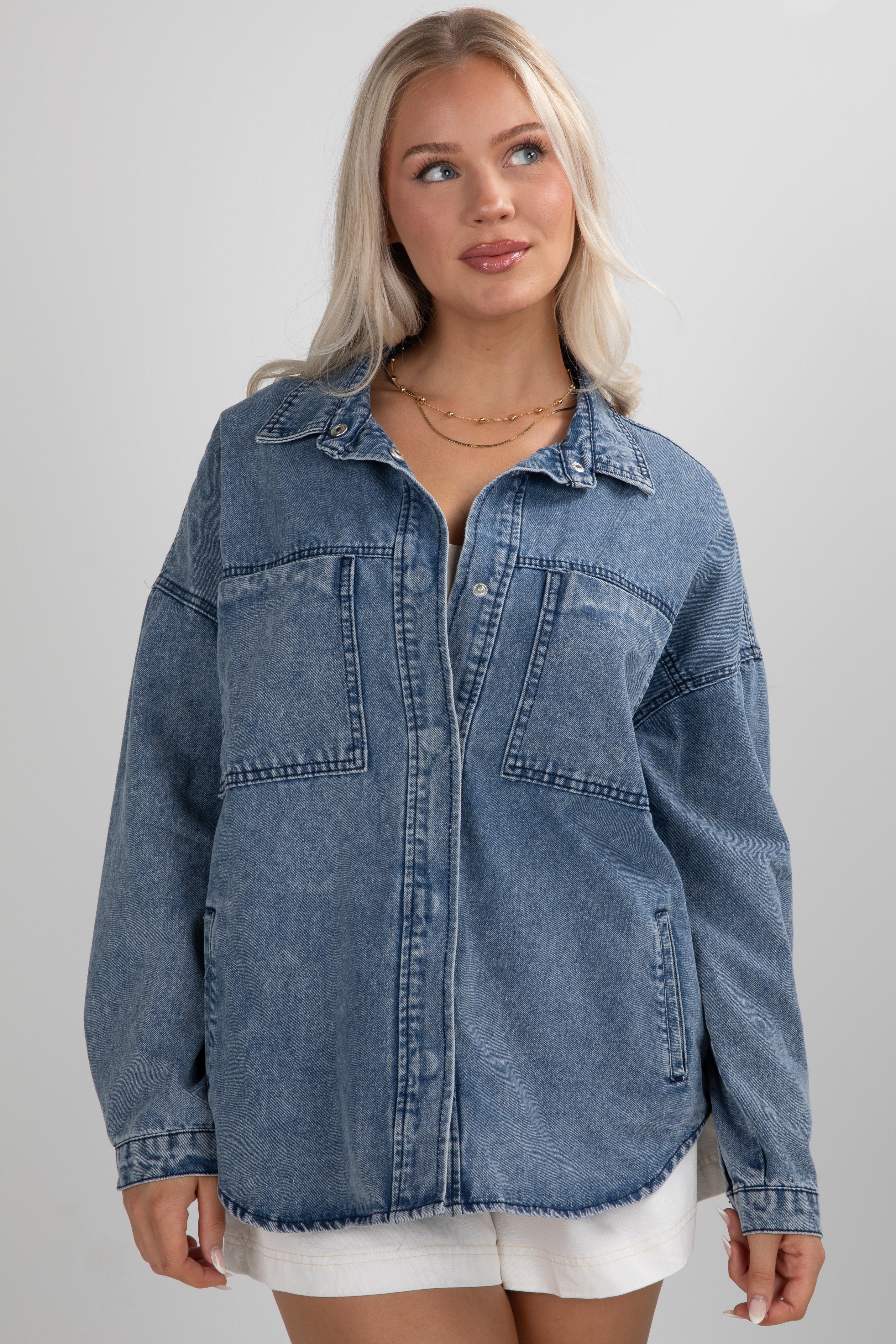 Woman wearing a blue denim jacket on a gray background