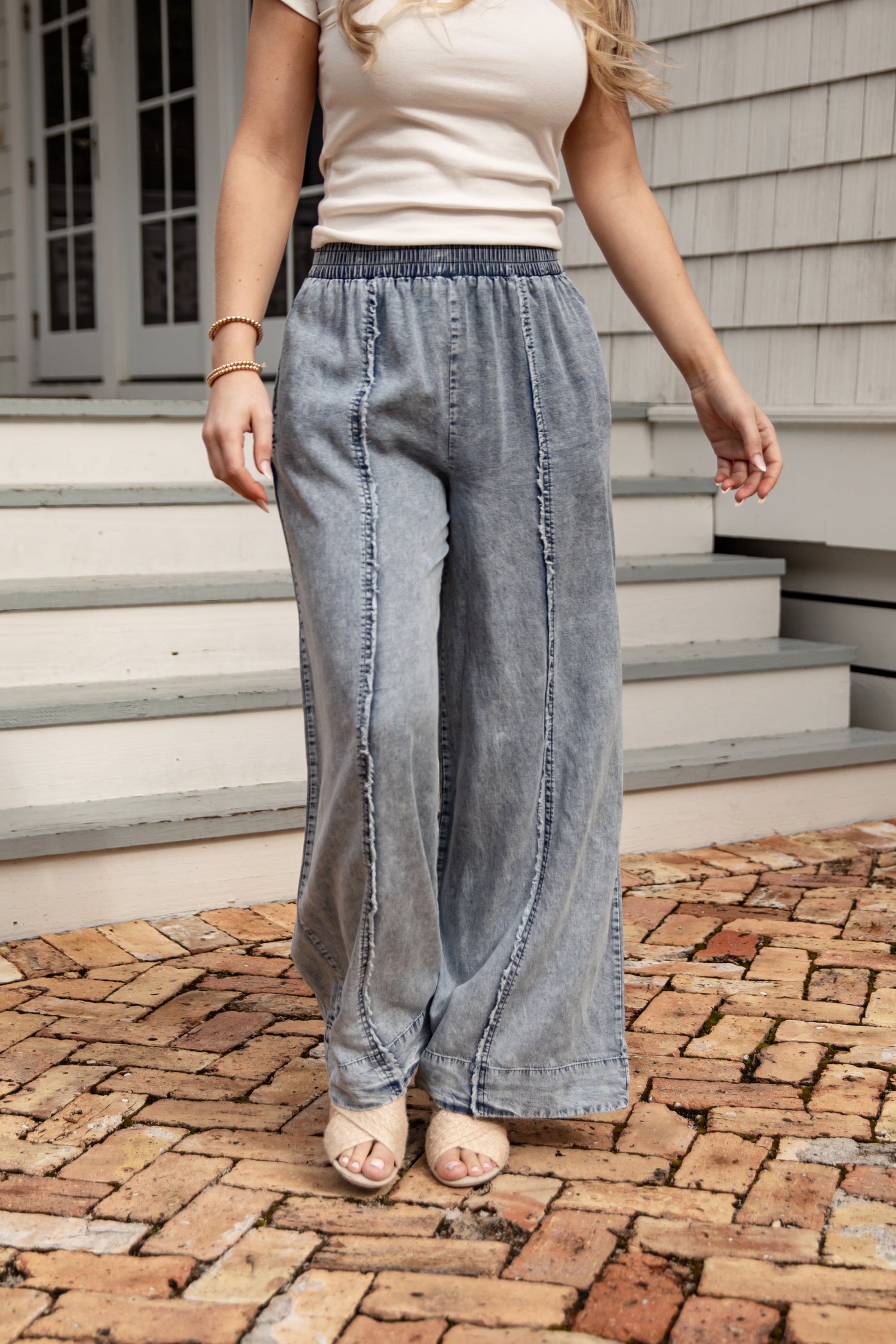 Person wearing wide-leg jeans standing on a brick patio.