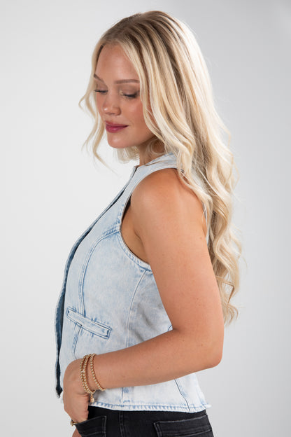 Woman wearing a light blue denim vest on a plain background