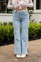 Person wearing light blue jeans and a pink floral top outdoors.