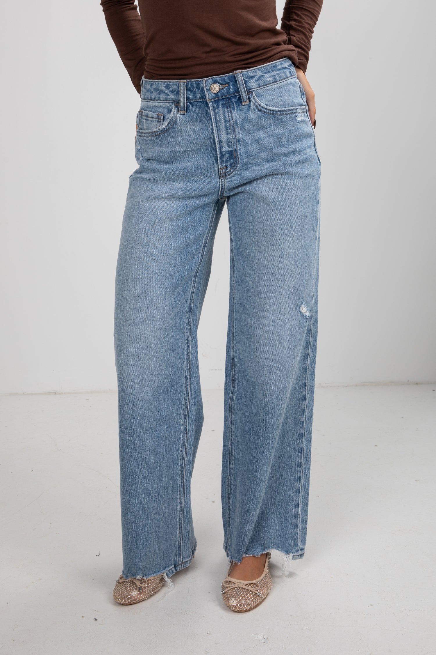 Person wearing light blue jeans on a white background