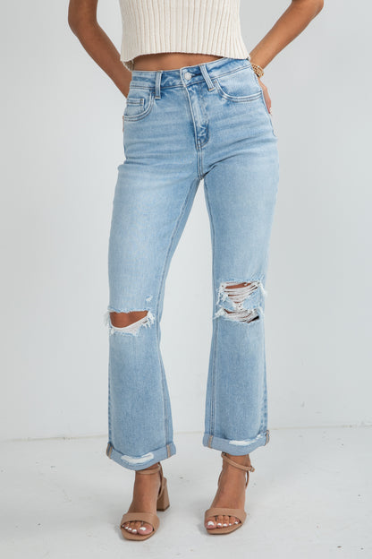 Light blue distressed jeans worn by a person on a white background