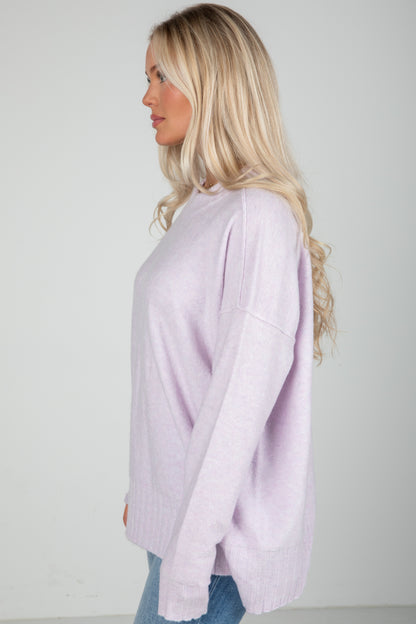 Woman wearing a light purple sweater against a plain background