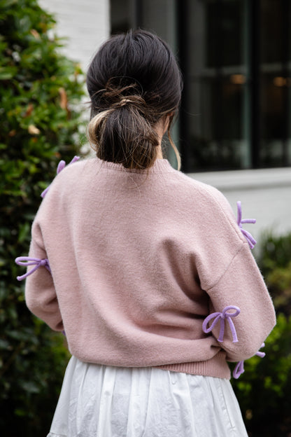 Person wearing a pink sweater with purple accents outdoors