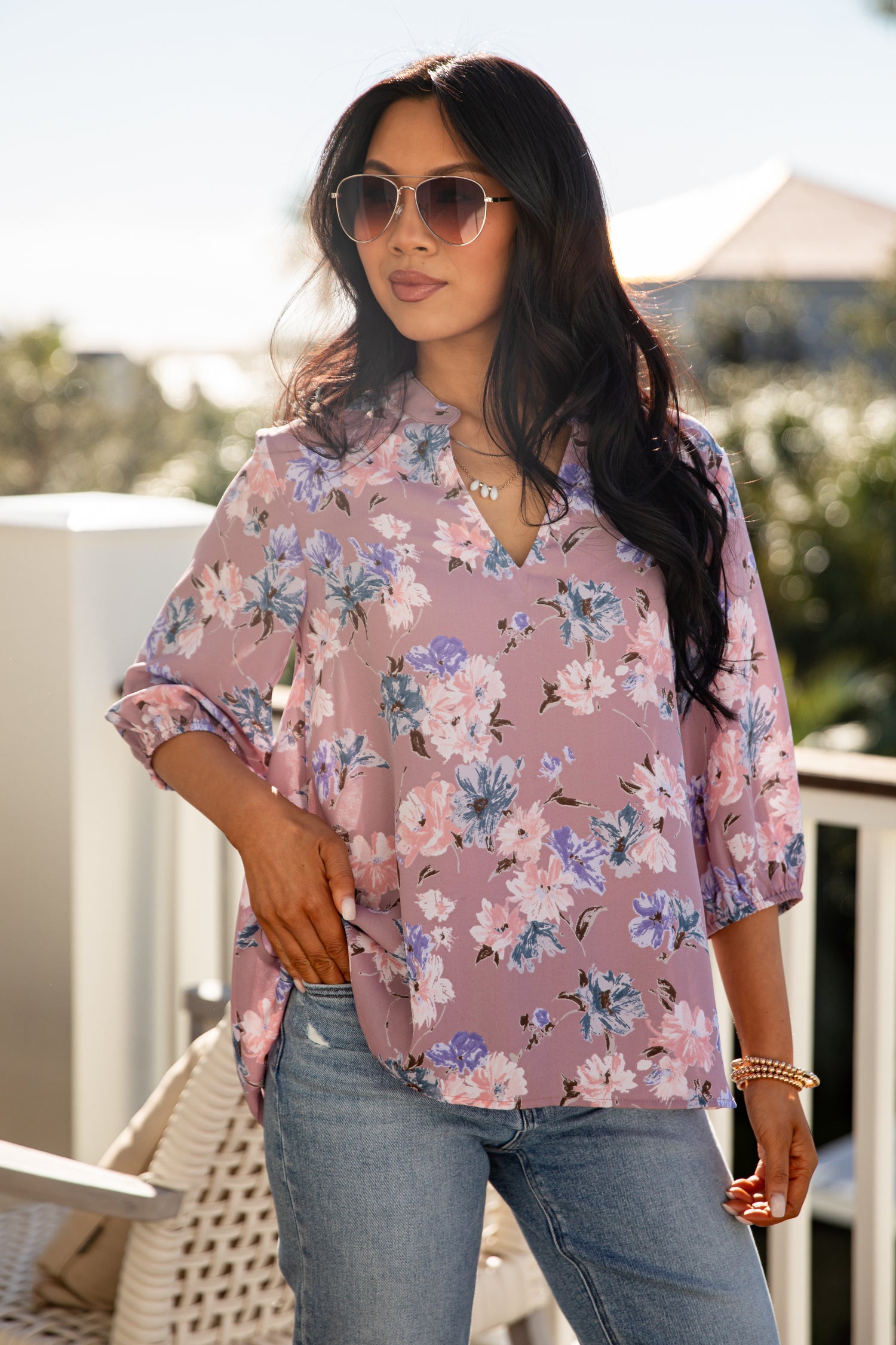 Woman wearing a floral blouse and sunglasses outdoors