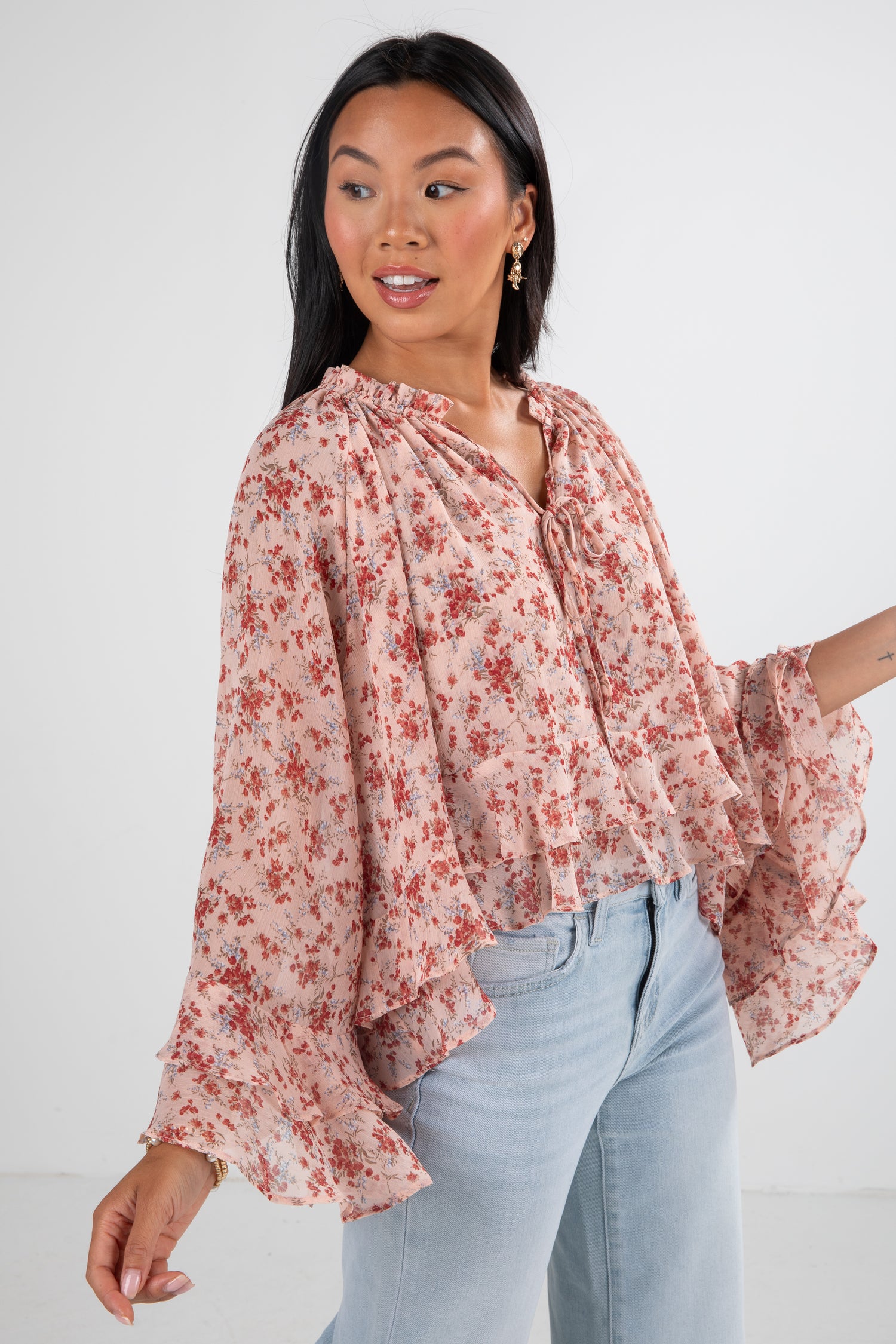 Woman wearing a floral blouse and light blue jeans on a white background