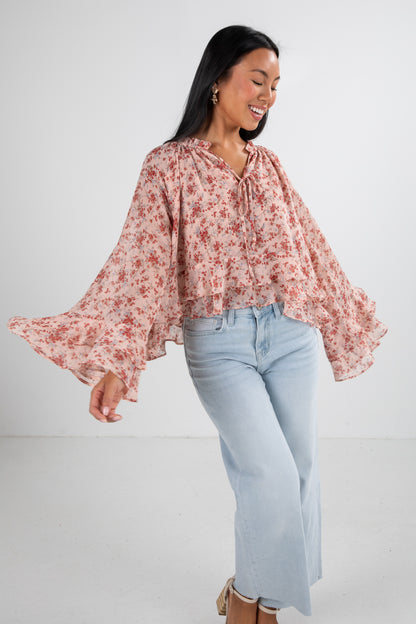 Woman wearing a floral blouse and light blue jeans on a white background
