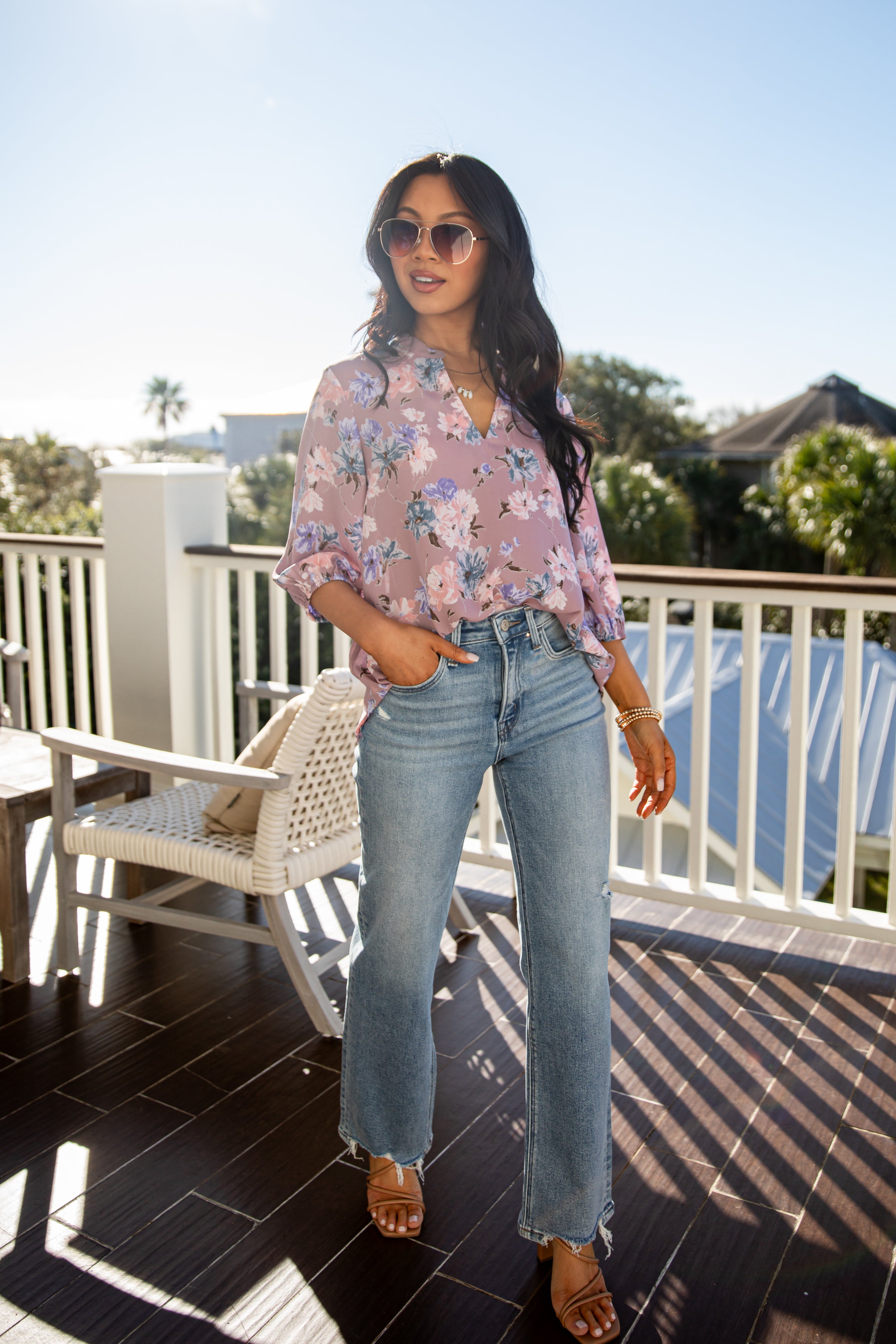 Woman wearing a floral blouse and jeans on a balcony