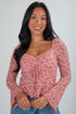 Woman wearing a pink floral long-sleeve top against a gray background
