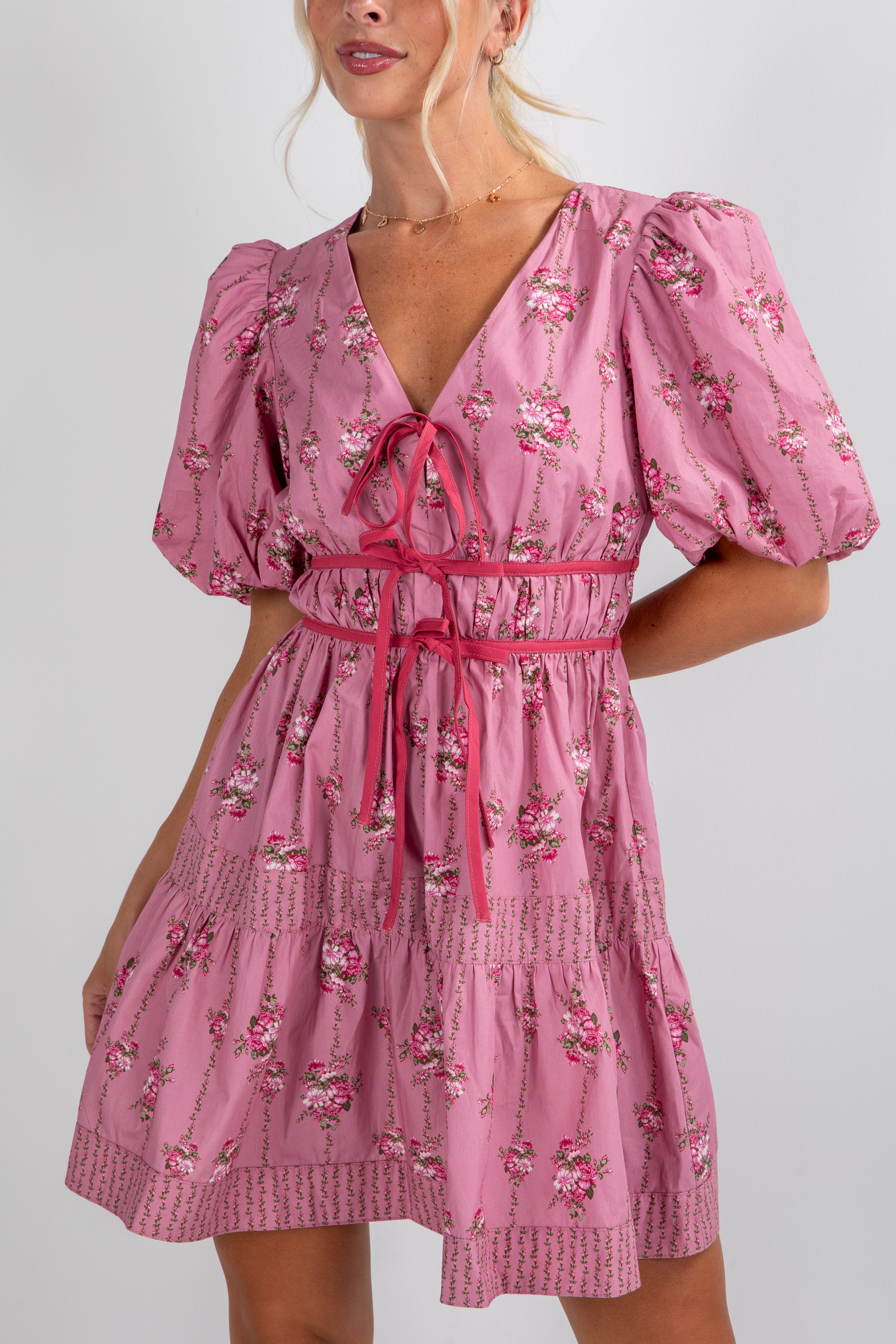 Woman wearing a pink floral dress with puff sleeves on a white background