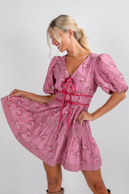 Woman wearing a pink floral dress with puff sleeves on a white background