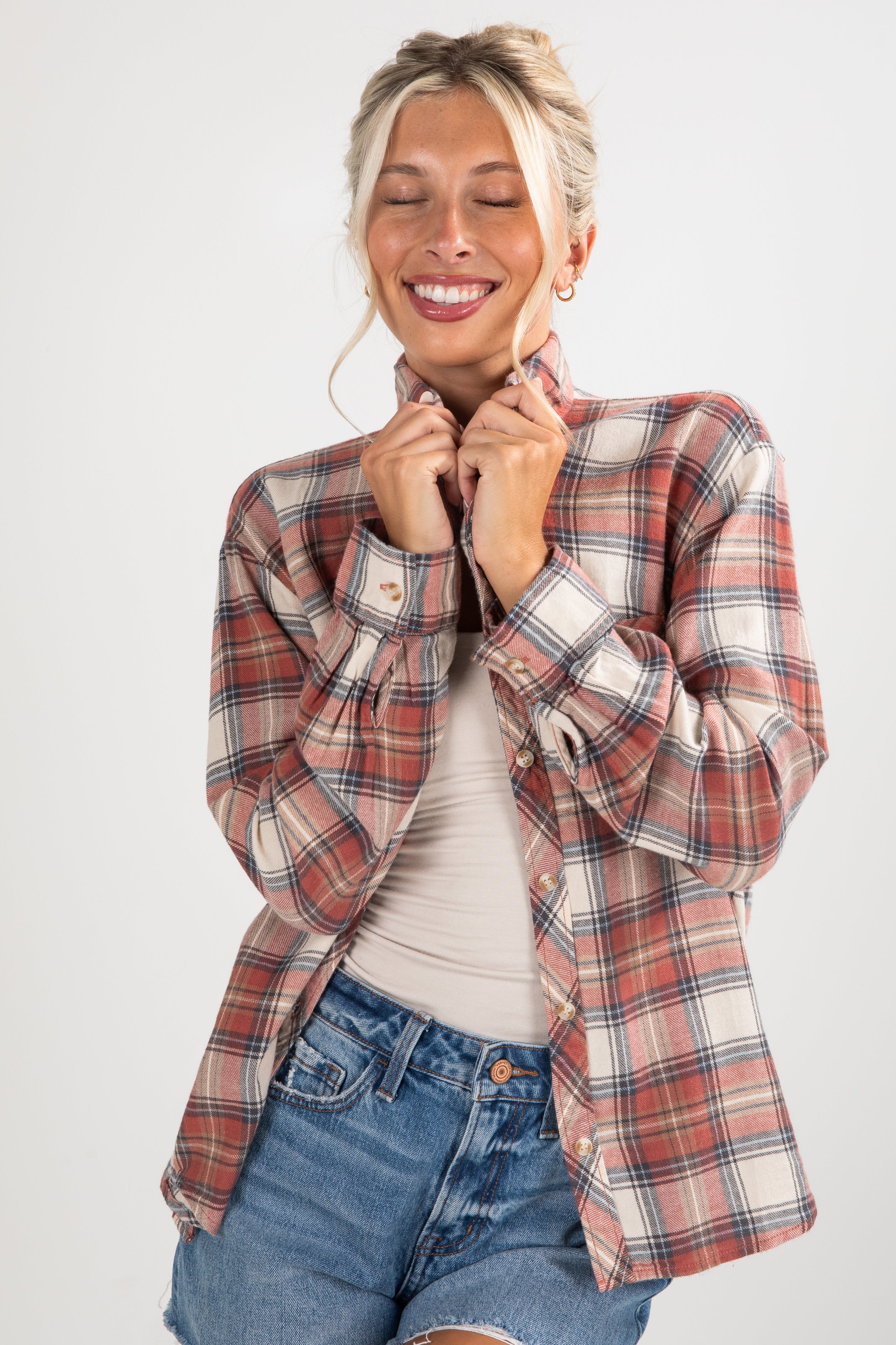 Woman wearing a plaid shirt and denim shorts on a white background
