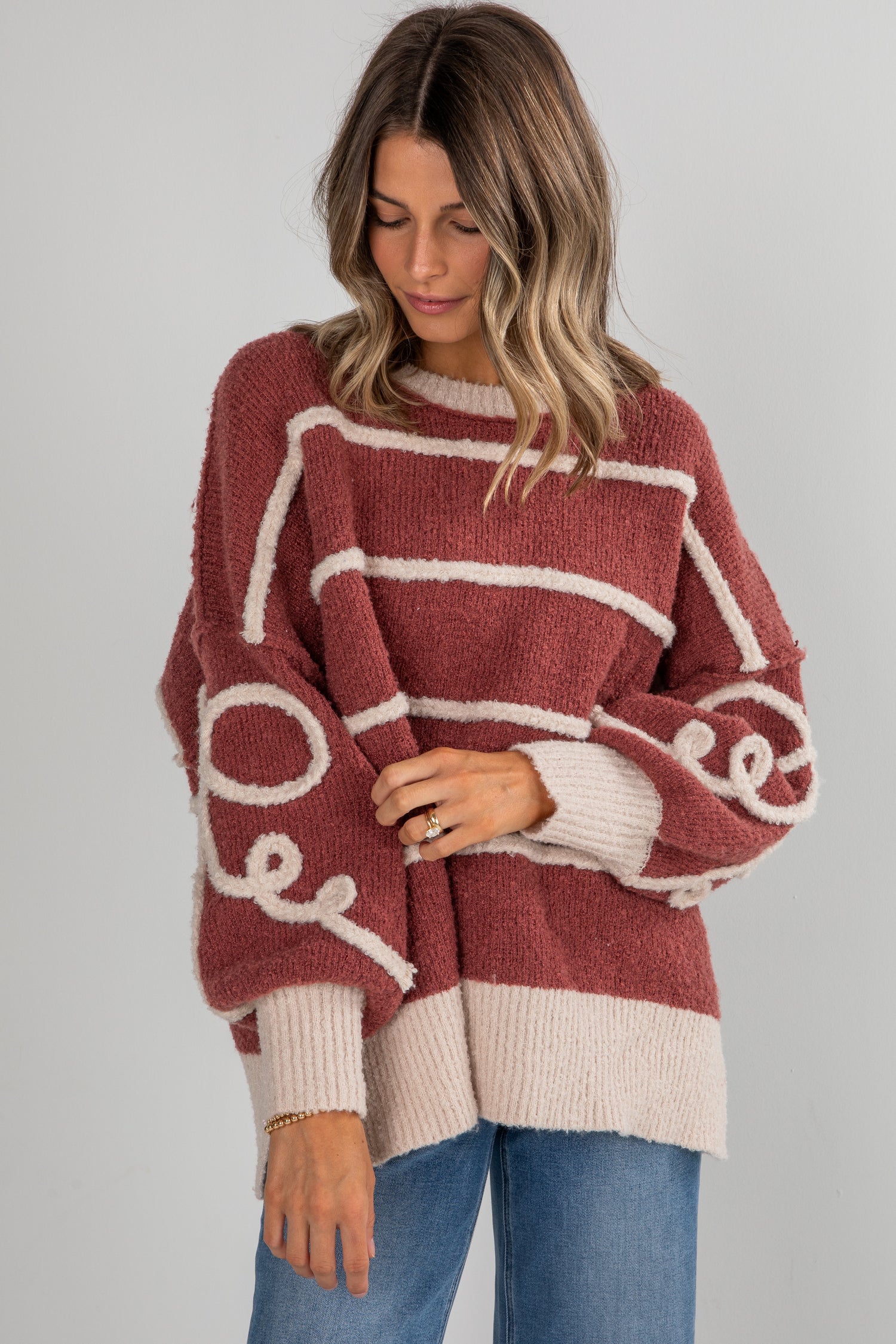 Woman wearing a maroon and beige sweater with &