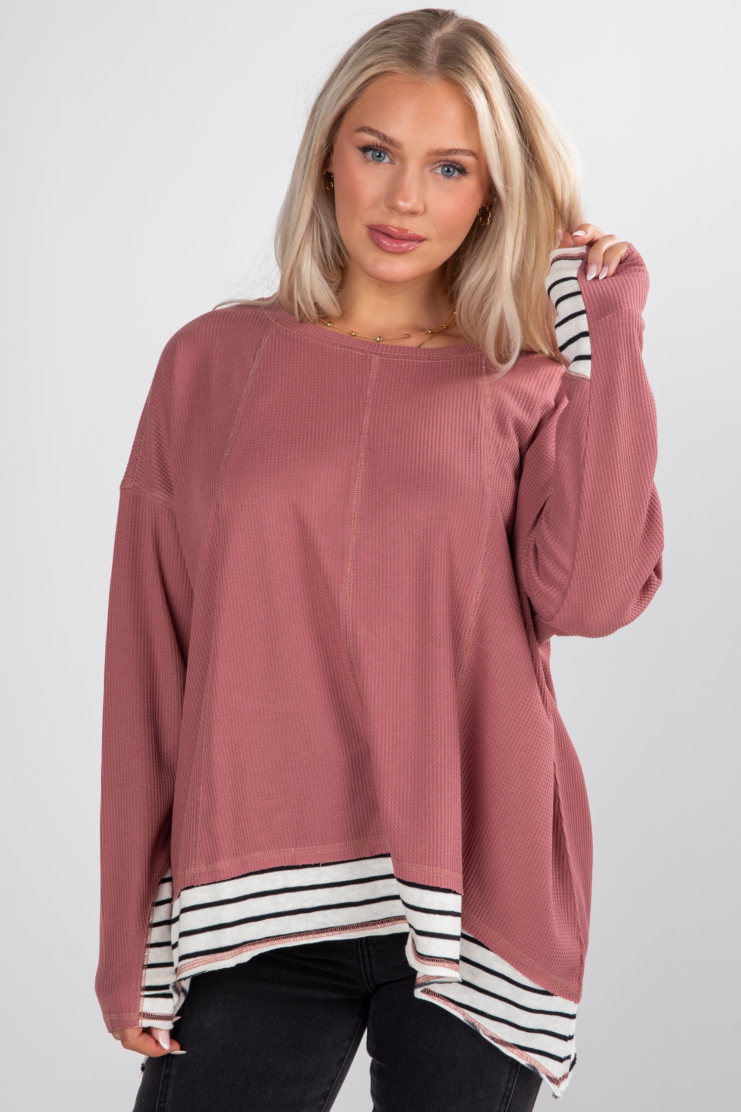 Woman wearing a pink sweater with a striped hem on a white background