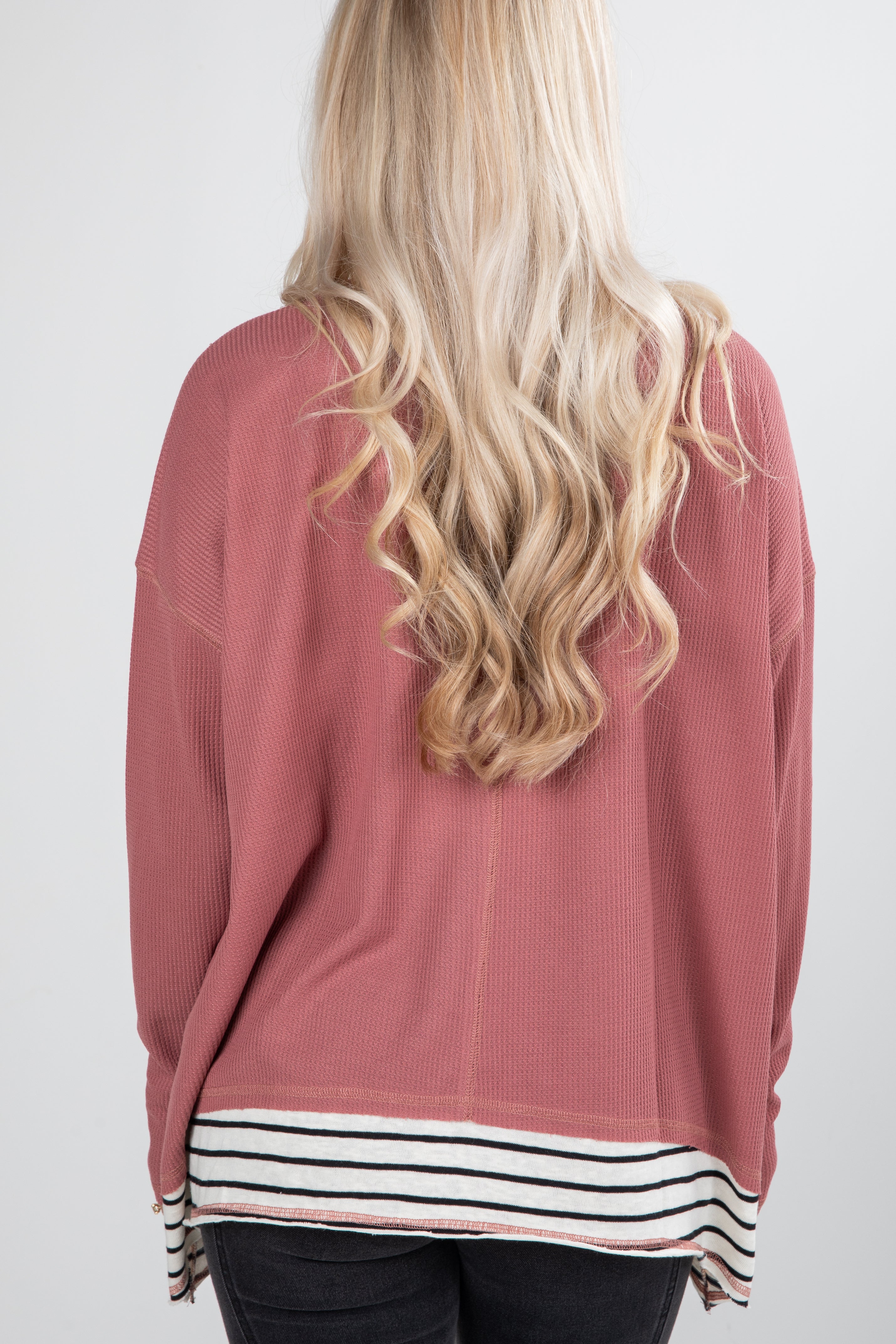 Person wearing a pink sweater with a white background