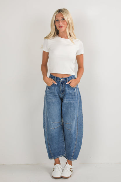 Woman wearing a white t-shirt and blue jeans on a plain background