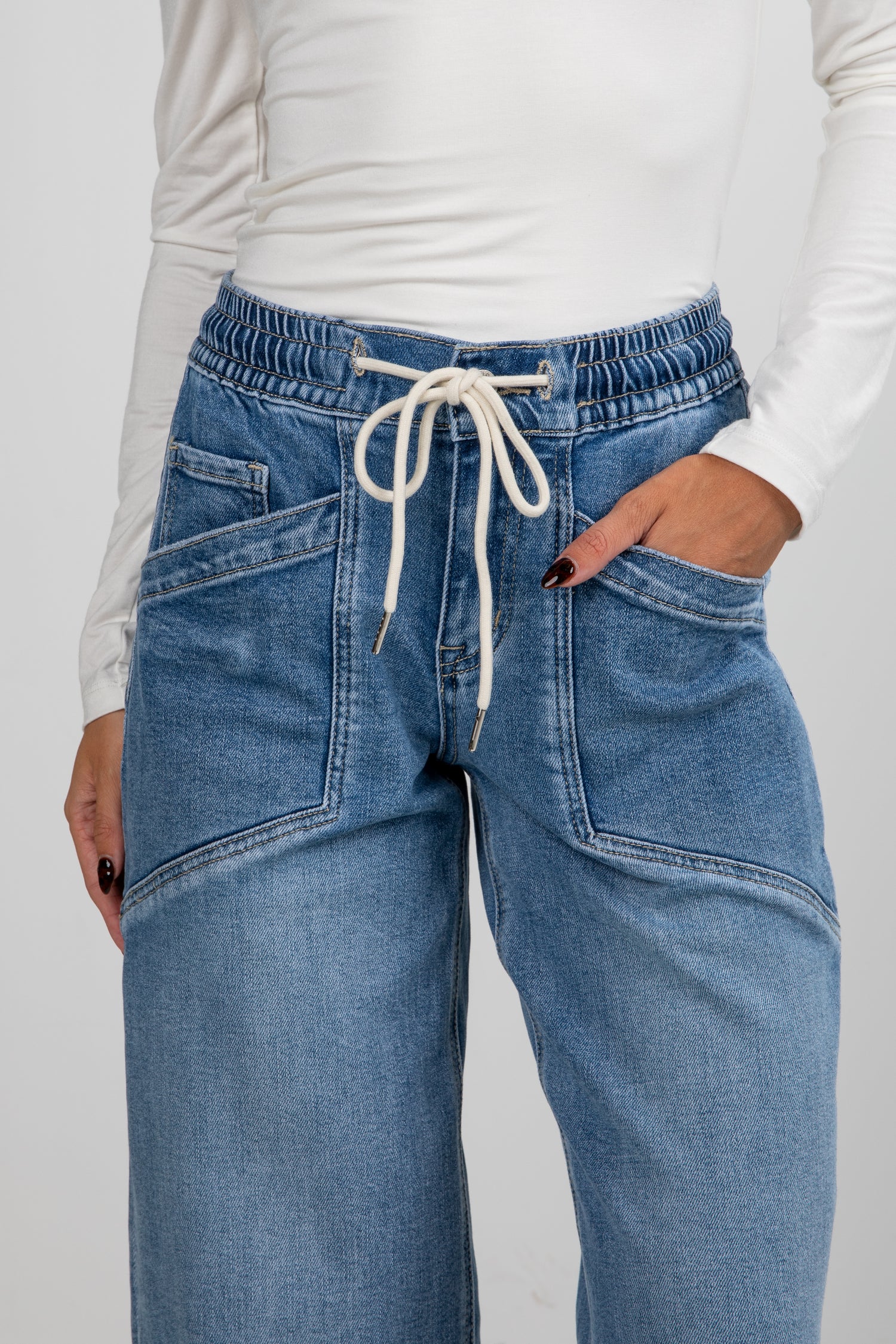 Blue jeans with a white drawstring on a plain background