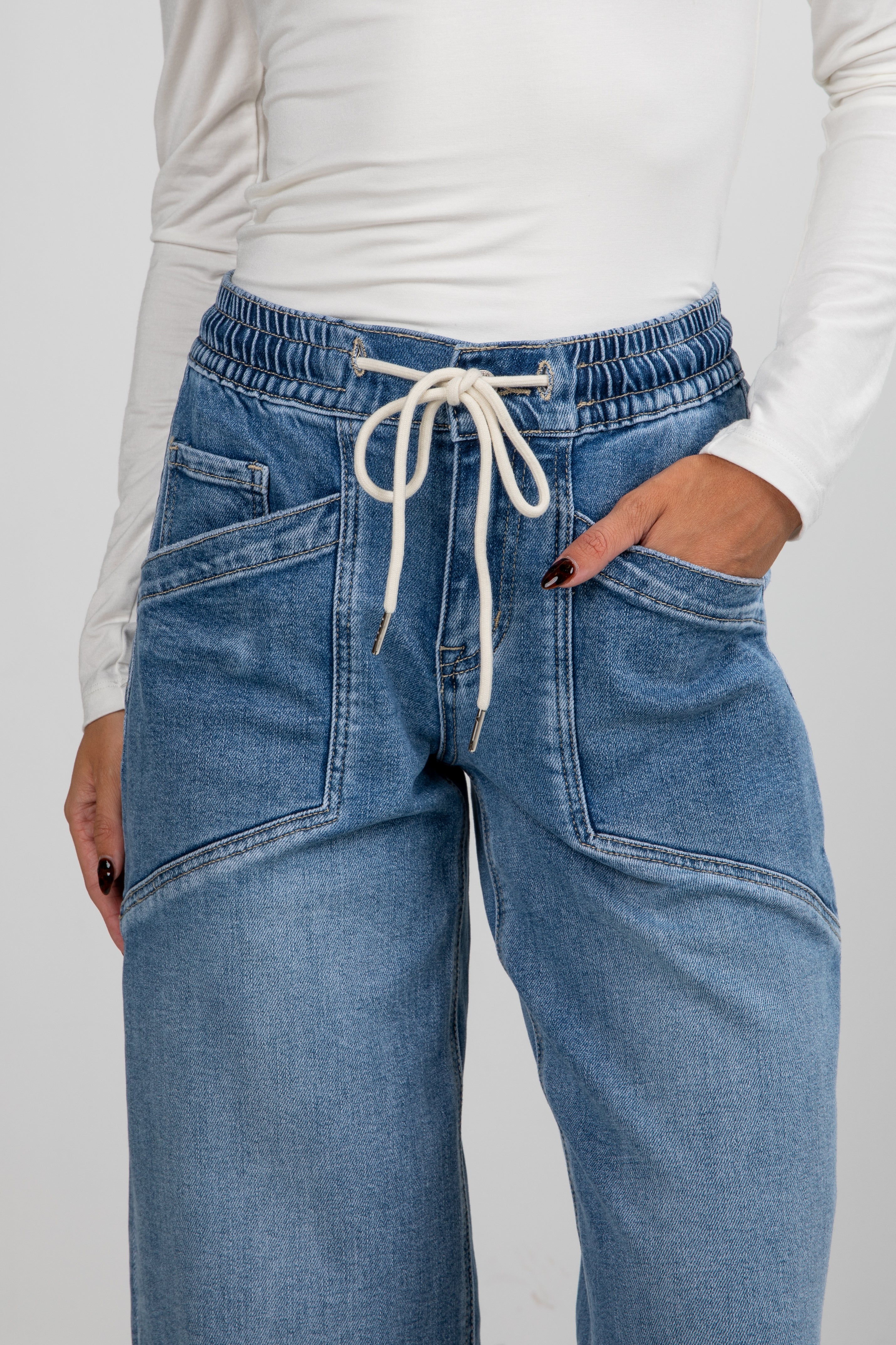 Blue jeans with a white drawstring on a plain background